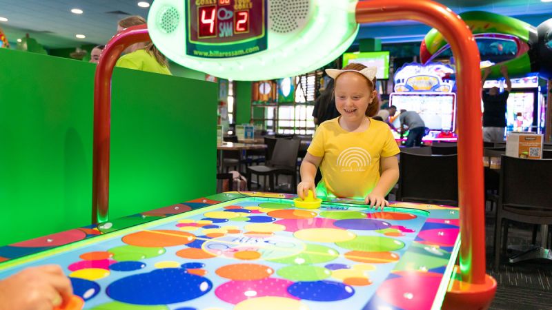 A young girl playing air hockey