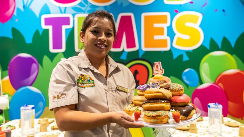 A Tabatinga employee holding a donut cake with a 4 candle